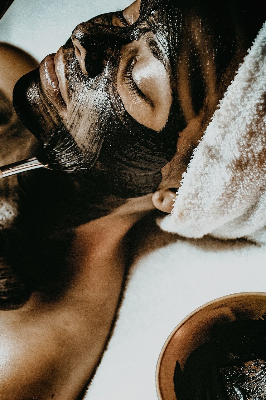 Mujer acostada recibiendo facial con charcoal