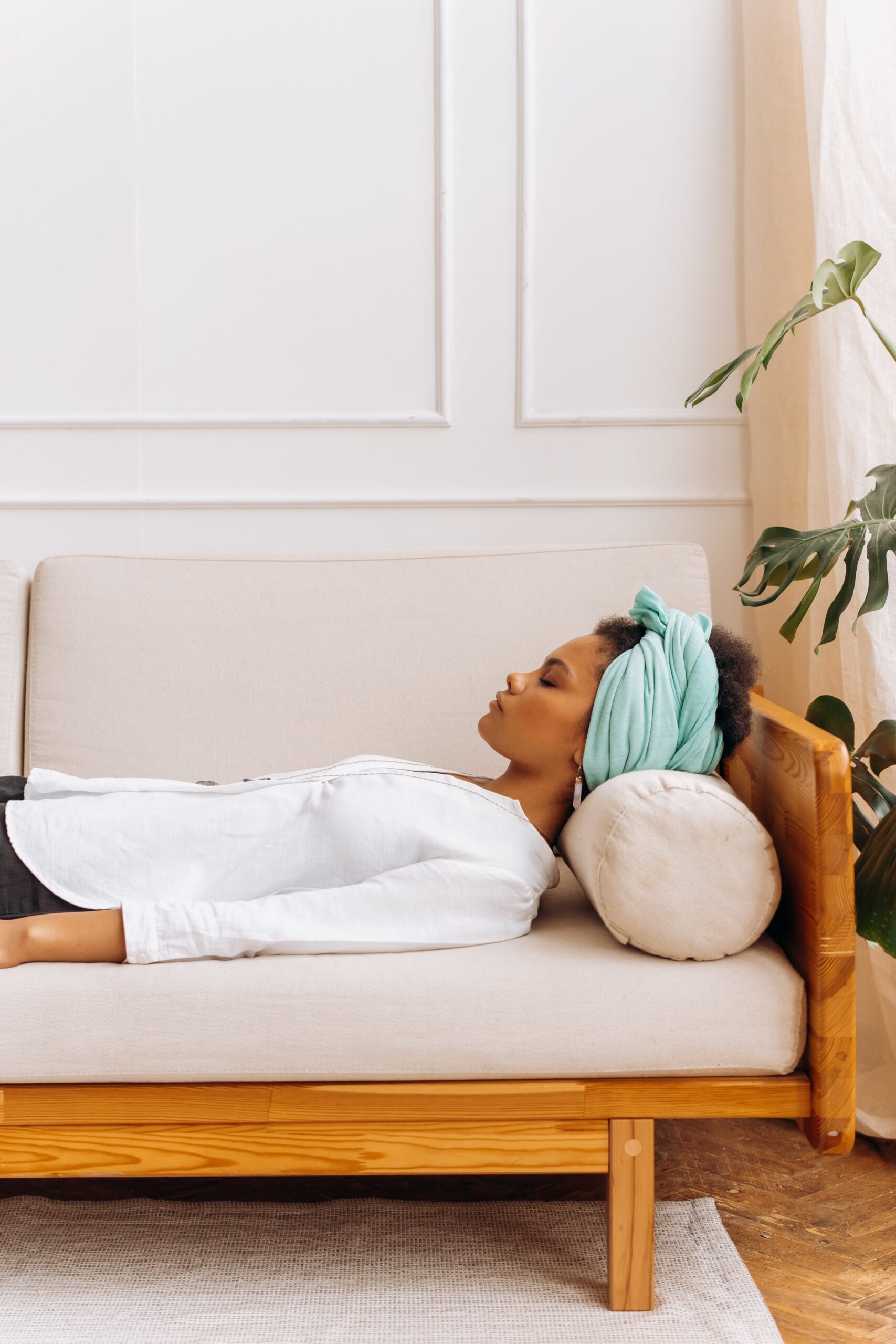 Mujer acostada en sofa con los ojos cerrados recibiendo una meditacion guiada